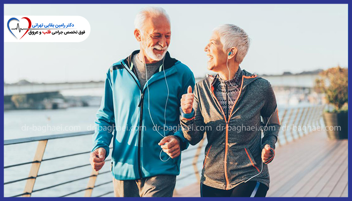 یک زوج سالمند خندان در حال پیادهروی و ورزش صبحگاهی در فضای باز با لباس ورزشی مناسب.